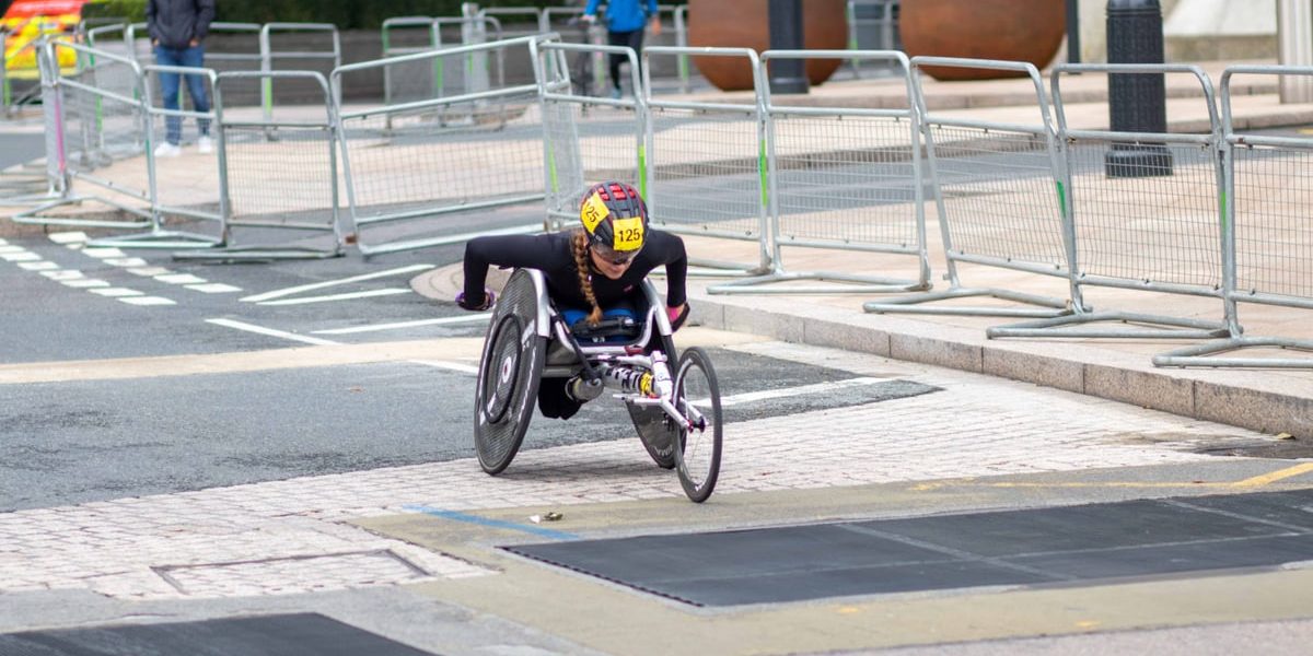 A dedicated athlete competes in a marathon using a racing wheelchair on city streets.