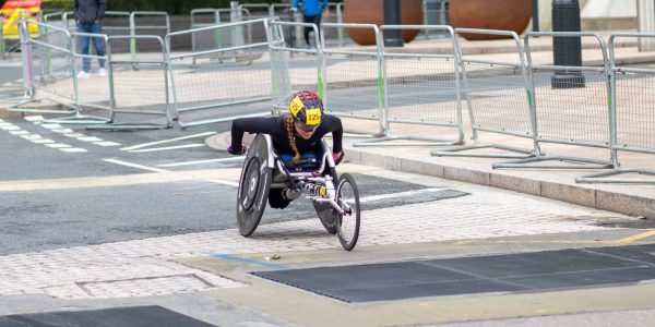 A dedicated athlete competes in a marathon using a racing wheelchair on city streets.